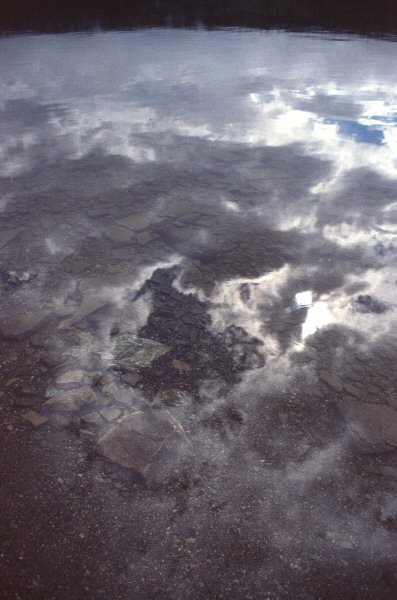 Wolken en zon weerspiegelen in het meer.