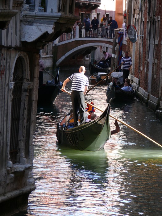 Licht valt op een gondola tussen de gebouwen.